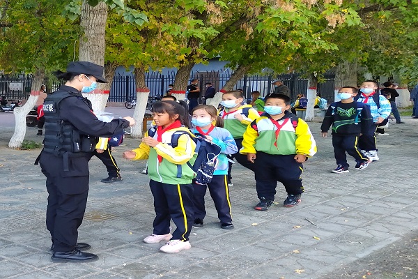 女子巡逻队队员为放学的小学生佩戴口罩